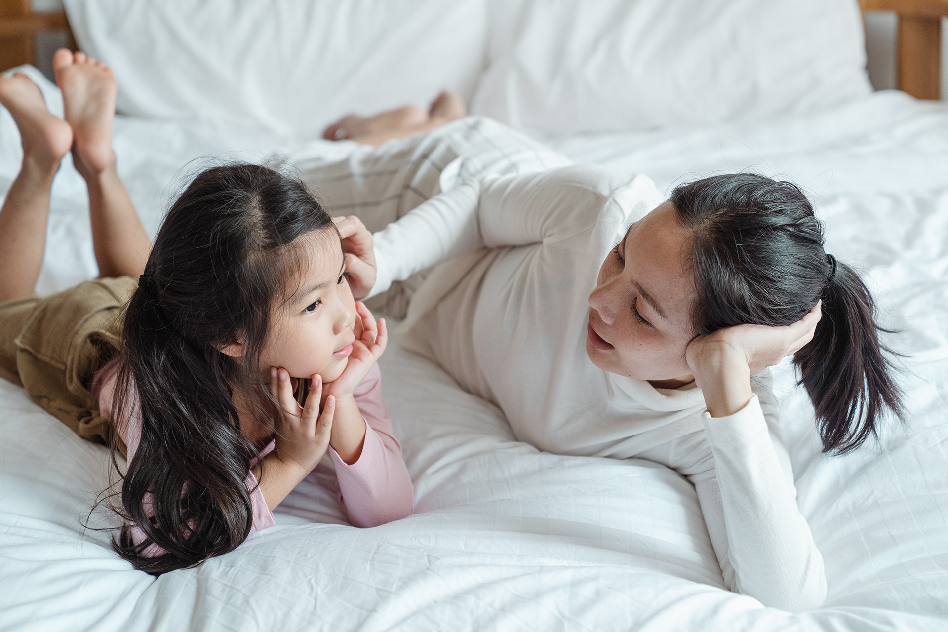 Mum and daughter on a bed relaxed, bonding and chatting