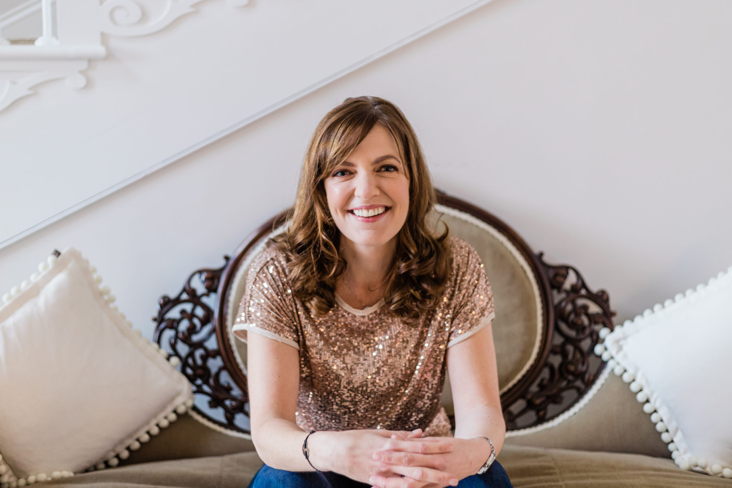 Sinead Doohan at The Happy Me wearing a gold sparkly top, sitting on a chair and smiling